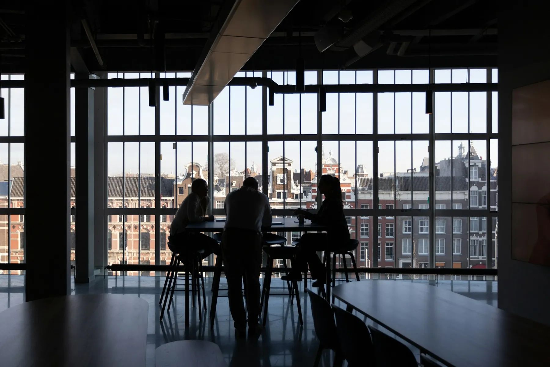 Beratungsgespräch am Tisch vor einer Fensterfront mit Blick auf Altbaufassaden