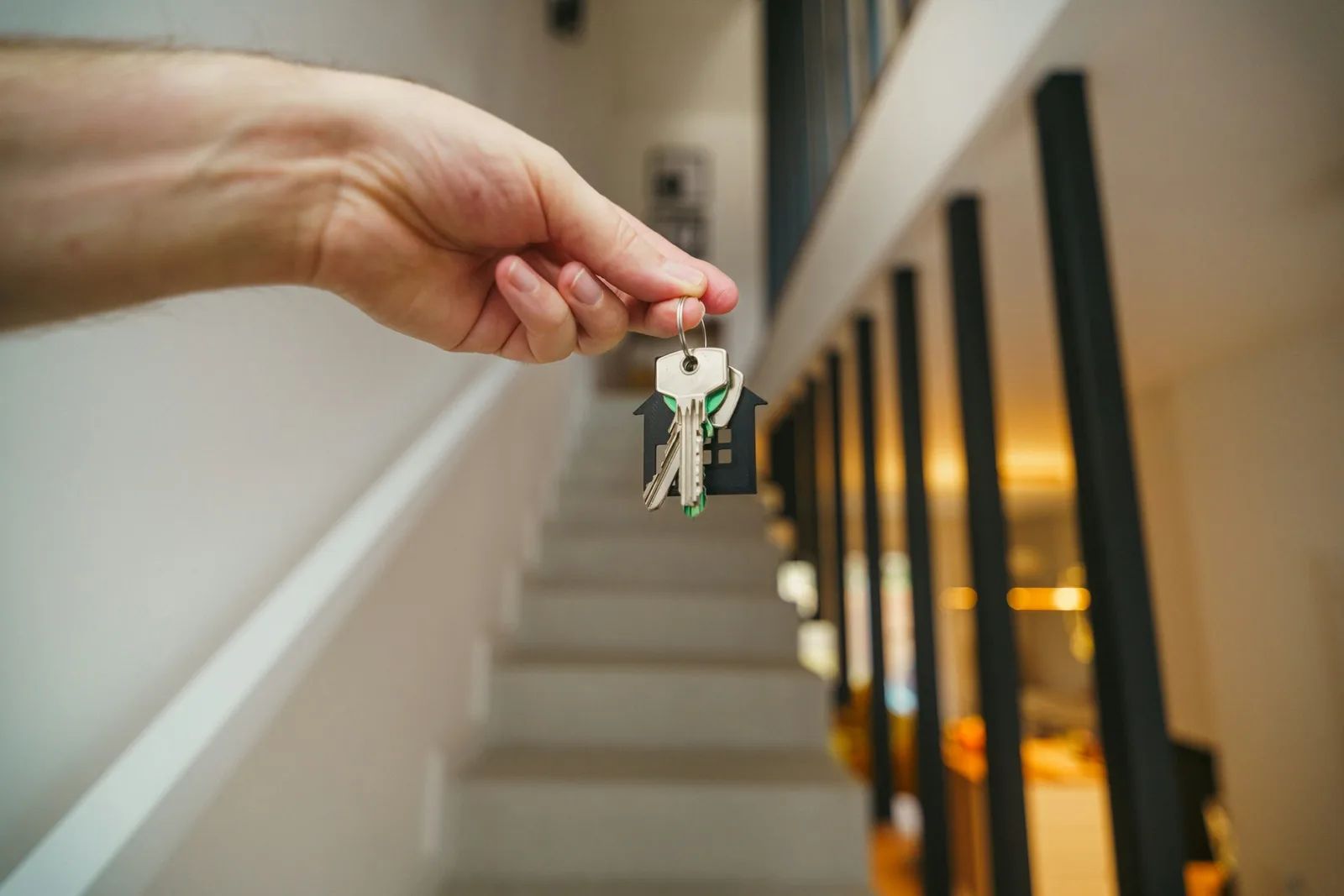 Hand übergibt Wohnungsschlüssel im Treppenhaus