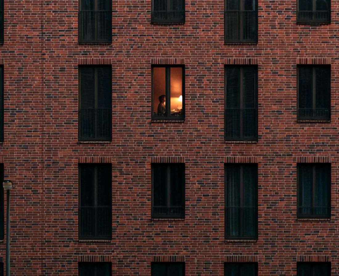 Sondereigentumsverwaltung Hamburg: moderne Klinkerfassade in der Dämmerung, nur in einer Wohnung brennt Licht